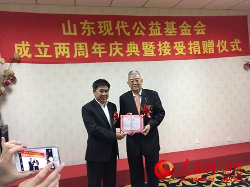 山东现代公益基金会穆宝林理事长向王新亭先生颁发爱心慈善大使聘书。